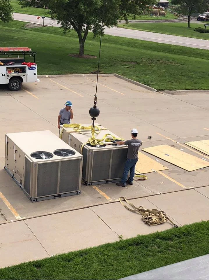Two of the thirteen new rooftop units staged in the lot before being hoisted at Tri County Schools