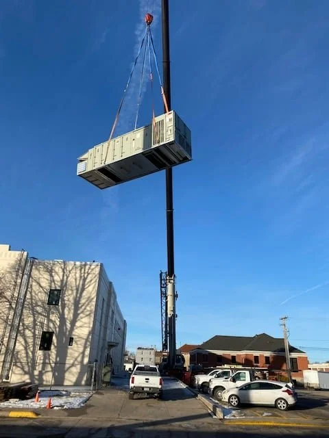 A rooftop unit suspended from the crane above the York City Auditorium