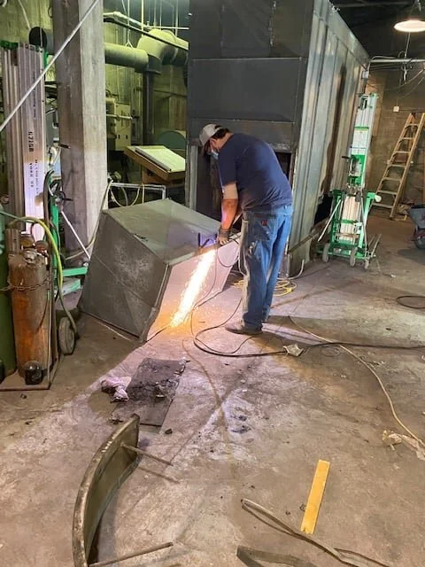 A technician torch-cutting the old boiler apart inside the York City Auditorium