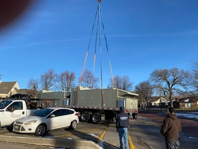 The crane lifting a new unit over the trees toward the York City Auditorium roof