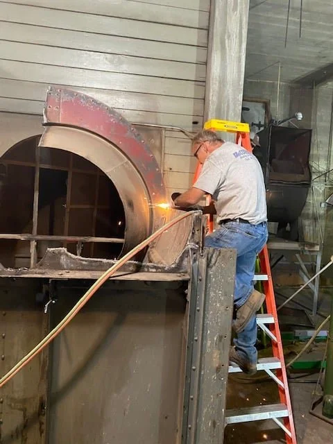 A technician fitting new ductwork into the brick air tunnel at the York City Auditorium