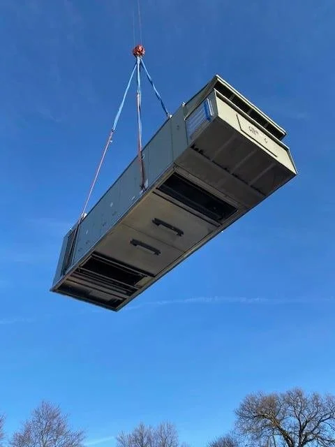 A new air handler hoisted overhead by crane at the York City Auditorium